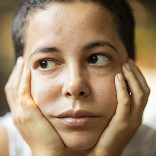 Person with hands on face displaying tired or stressed expression, suggesting dental pain or fatigue.