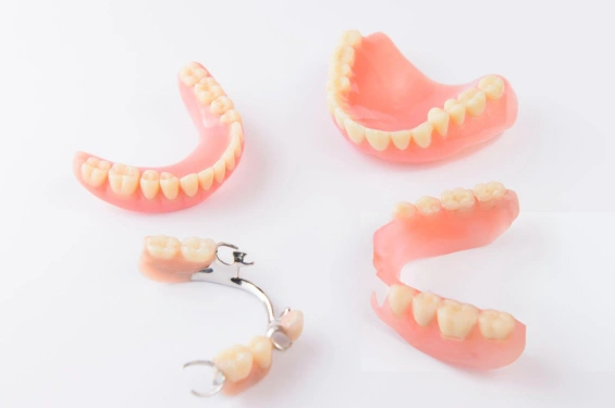 Dental prosthetics display featuring multiple dentures and clasps on white background